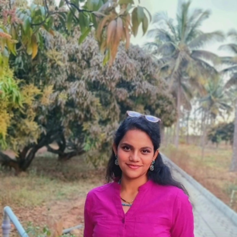 Indian woman wearing a pink shirt, smiling. 