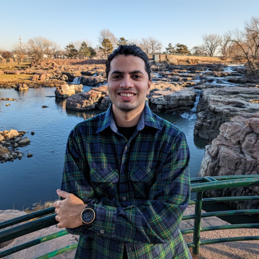 Photo of Gavin Silveira crossing his arms and smiling in front of a waterfall